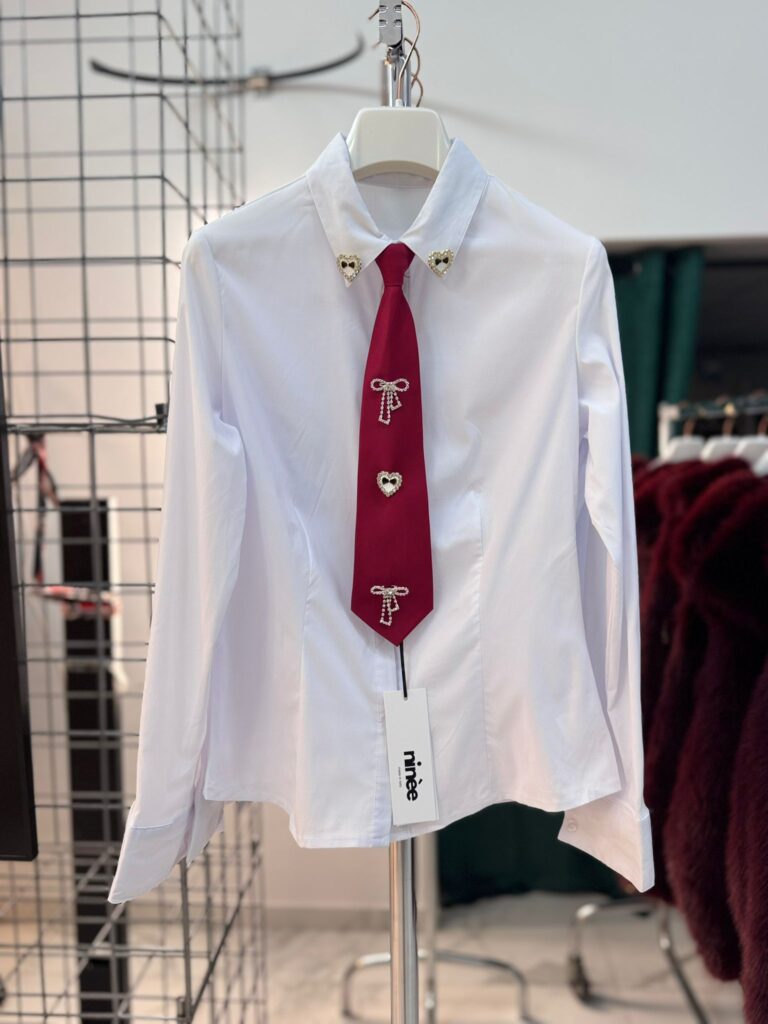 Camicia con cravatta e spille decorative nella parte frontale